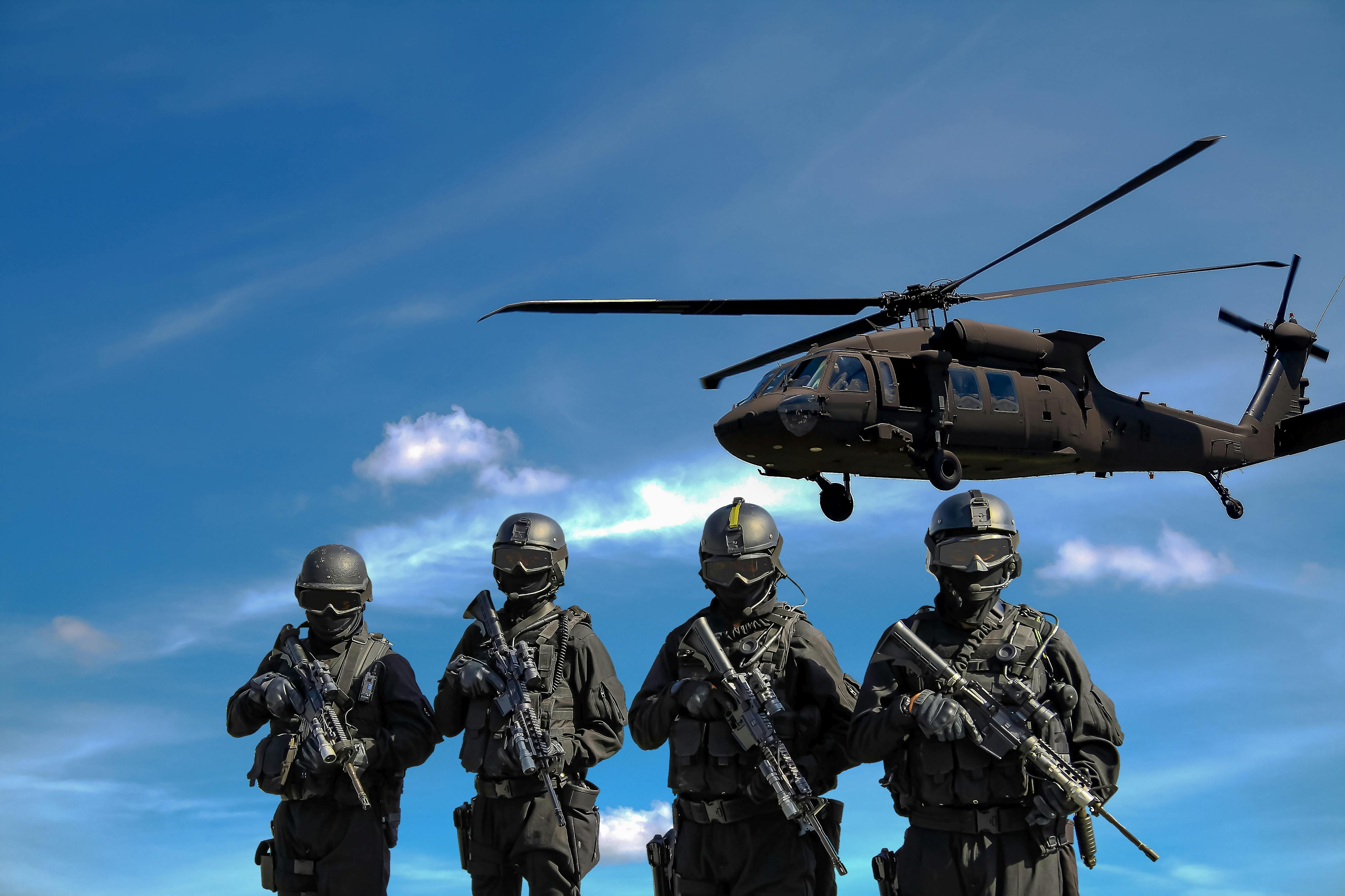 Military men with a helicopter in flight above them