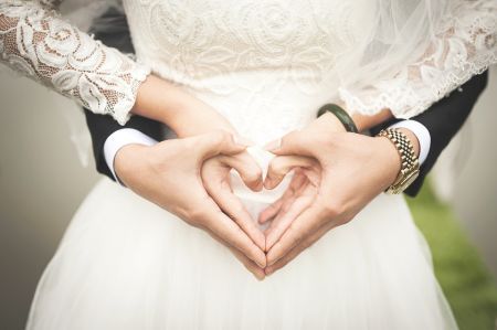 married couple with heart hands