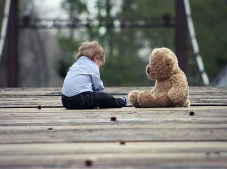 kid and teddy bear on bridge